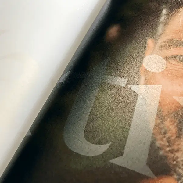 Nahaufnahme einer bedruckten Seite, welches durchlässige weisse Buchstaben auf einem Foto zeigt