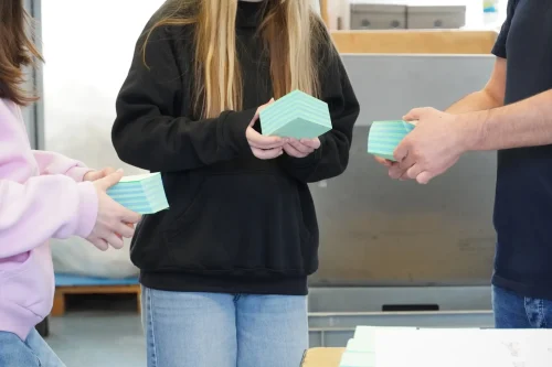 Zwei Schülerinnen halten einen Stapel Papier in ihren Händen und erstellen einen spiralförmigen Drehblock