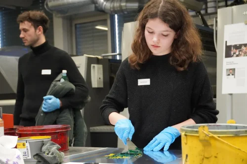 Eine Schülerin mischt im Offsetdruck Farben mit einem Spachtel
