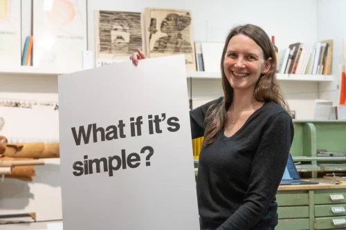 Eine Lehrerin zeigt ihr selbst gedrucktes Plakat in die Kamera