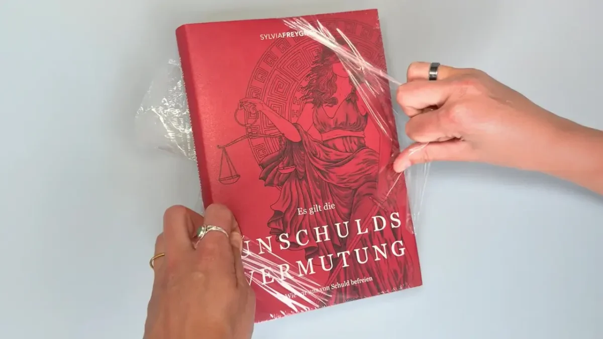 Welttag des Buches: Ein neues Buch wird aus der Klarsichtfolie ausgepackt